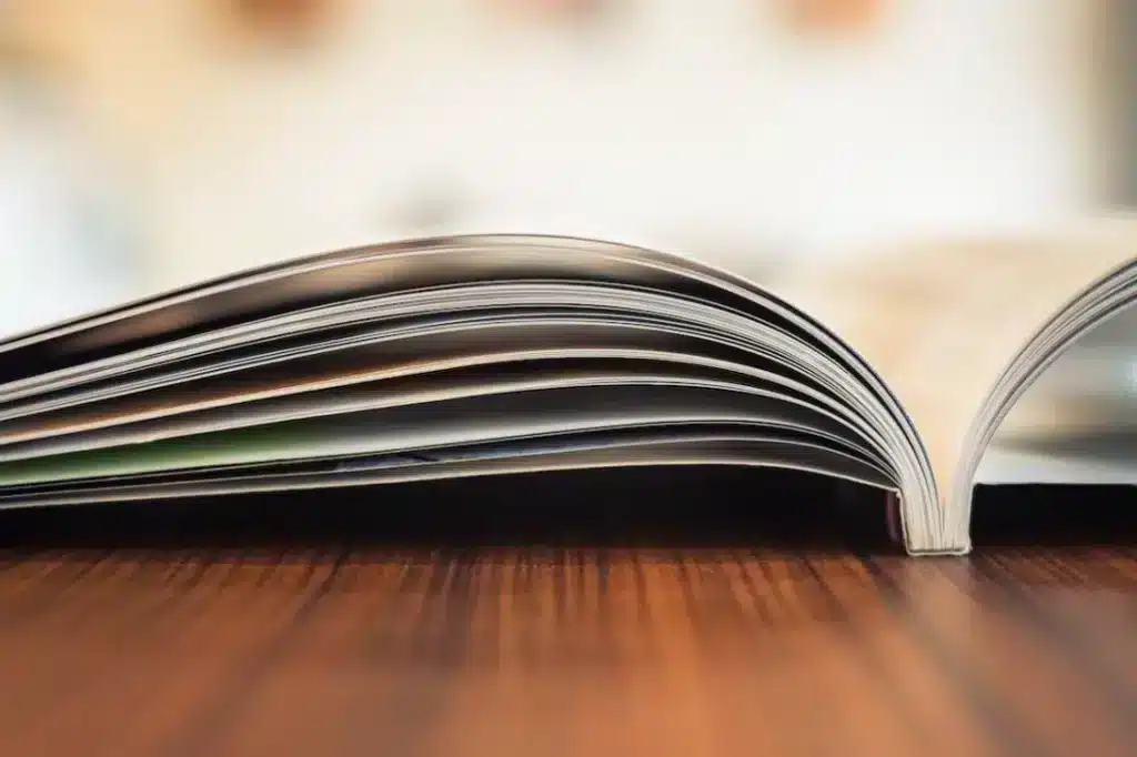 Offenes Magazin liegt flach auf einem hölzernen Tisch, fokussiert auf den gebogenen Seitenrand.