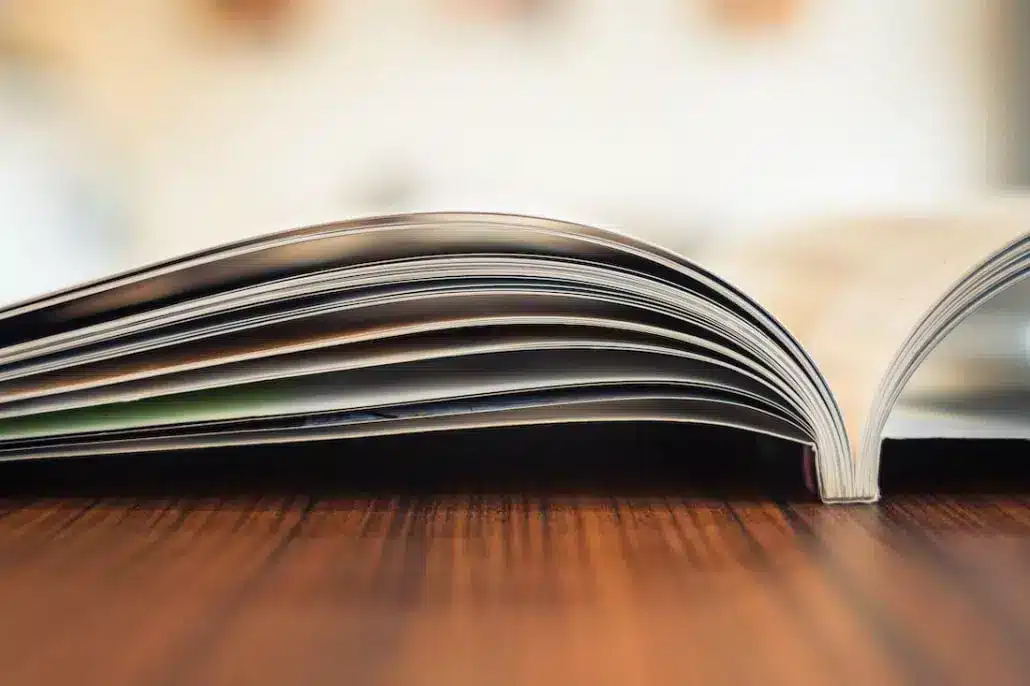Offenes Magazin liegt flach auf einem hölzernen Tisch, fokussiert auf den gebogenen Seitenrand.