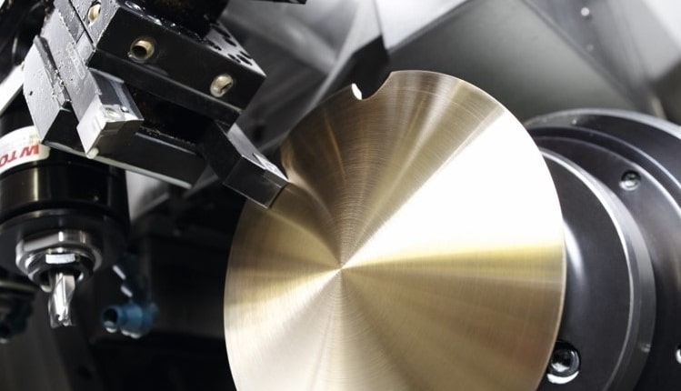 Eine CNC-Maschine beim Drehen eines glänzenden Metallbauteils, die massive Pendellinse