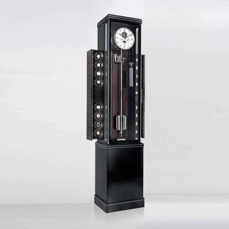 Hohe, glänzende Standuhr Troja Lunaris von Erwin Sattler mit verglastem Gehäuse und sichtbarem Uhrwerk, flankiert von 16 Armbanduhren.