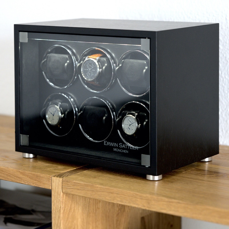 Uhrenbeweger Rotalis 6 von Erwin Sattler mit sechs Uhren, in einem eleganten schwarzen Gehäuse auf einem Holztisch platziert.