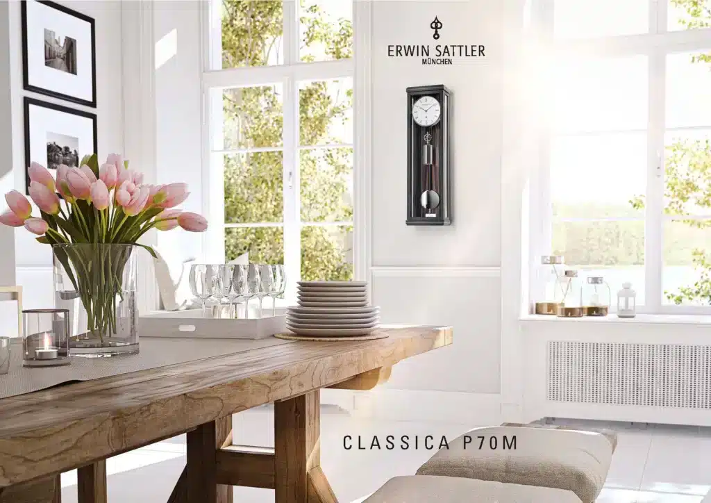 Großes Wohnzimmer mit Holz-Esstisch, darauf ein Glasvase mit rosa Tulpen und Geschirr. An der Wand hängt die Pendeluhr Classica P70M und die Aufschrift "Erwin Sattler München". Sonnenlicht strömt durch große Fenster.
