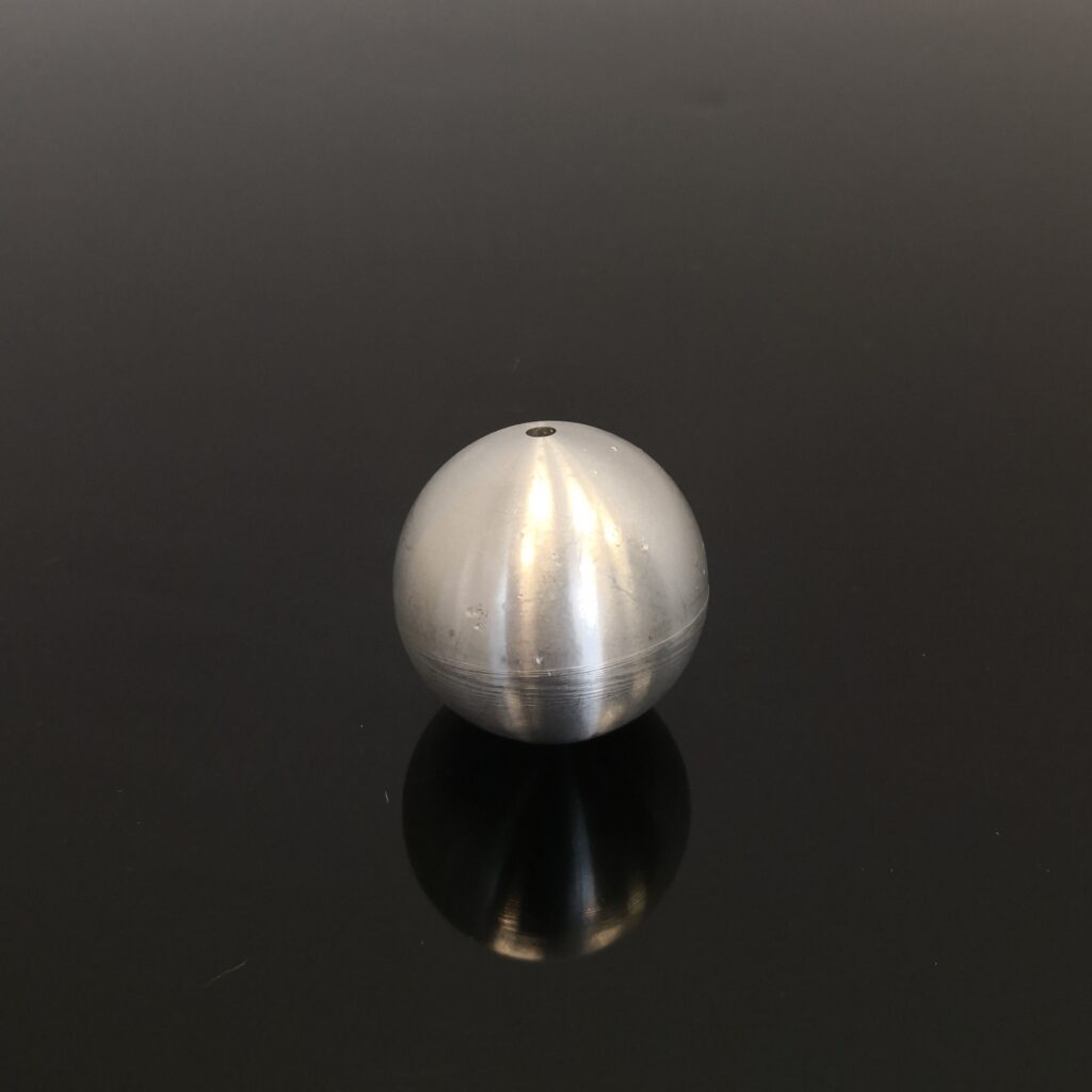 Eine glänzende Metallkugel auf schwarzem Hintergrund, die ihr Spiegelbild auf der Oberfläche zeigt.