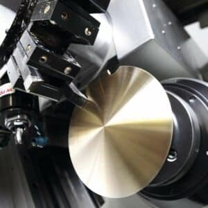 Eine CNC-Maschine beim Drehen eines glänzenden Metallbauteils, die massive Pendellinse