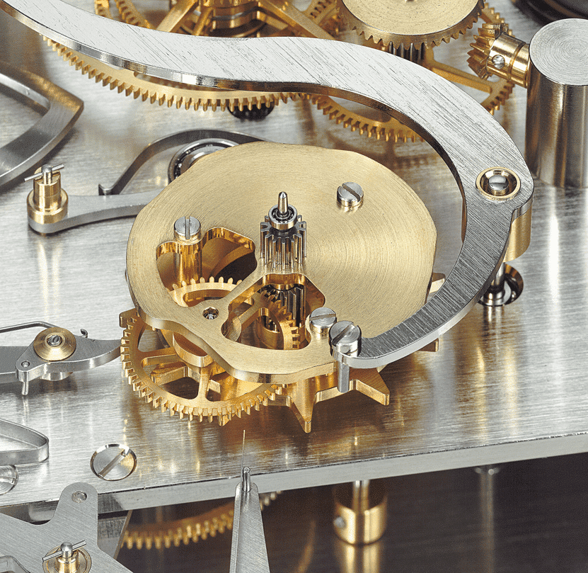 Nahaufnahme eines Uhrwerks mit Zahnrädern aus glänzendem Messing und silberfarbenen Metallelementen.