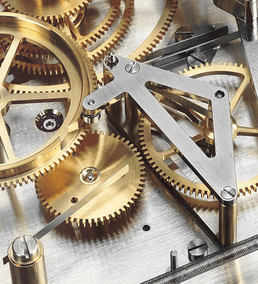 Nahaufnahme eines Uhrwerks mit mehreren ineinandergreifenden Zahnrädern aus Messing und silbernen Metallkomponenten.