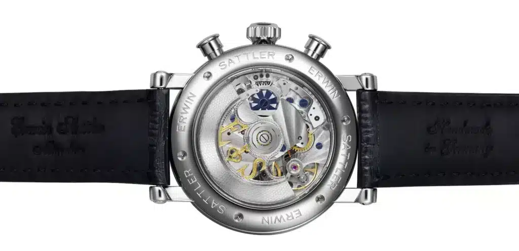 Rückseite der Armbanduhr Chronohgraph IIS von Erwin Sattler mit Glas im Gehäuse, das das Uhrwerk zeigt. Das Edelstahl Gehäuse ist mit einem schwarzen Lederarmband versehen. Rund um das Gehäuse ist der Name "ERWIN SATTLER" graviert.