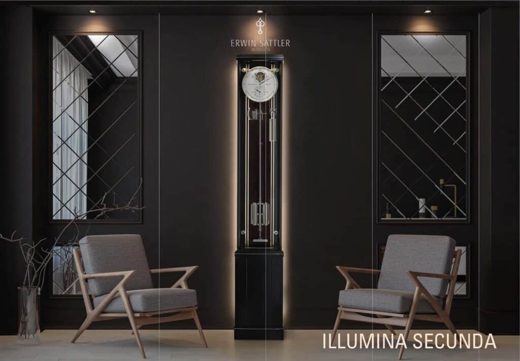 Große Standuhr Illumina Secunda in schwarz-braun von Erwin Sattler mit beleuchtetem Gehäuse in einem modern eingerichteten Raum, flankiert von zwei grauen Sesseln und dekorativen Wandspiegeln.