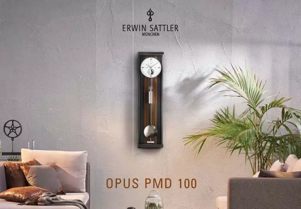 Wanduhr von Erwin Sattler, Modell OPUS PMD 100, an einer Wohnzimmerwand zwischen einem Sofa und einer Pflanze, mit hellem Hintergrund und minimalistischem Design.