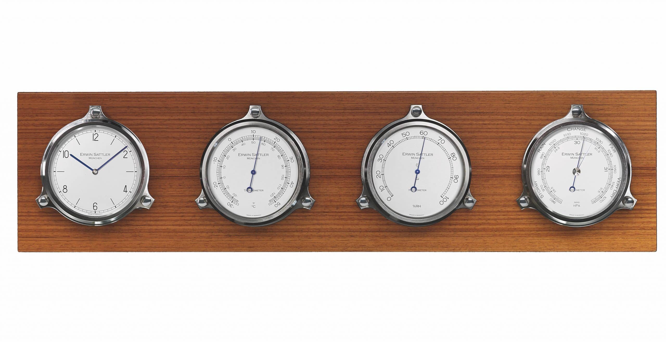 Vier nautische Instrumente von Erwin Sattler auf einem hölzernen Paneel: die Uhr ist das Modell Navalis, ein Thermometer, ein Hygrometer und ein Barometer, alle mit weißen Zifferblättern und blauen Zeigern.