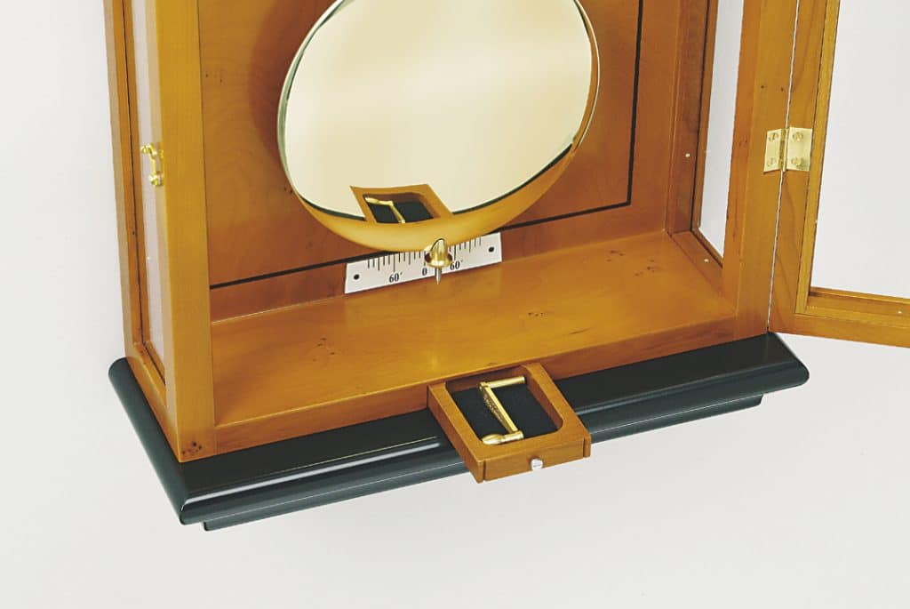 Detailausschnitt von einem Gehäuse der Wanduhren mit klassischem Gehäuse mit Sims und Sockel. Zu sehen ist das herausziehbaren kleine Schubladenelement im Sockel der Wanduhr für die Aufzugskurbel.