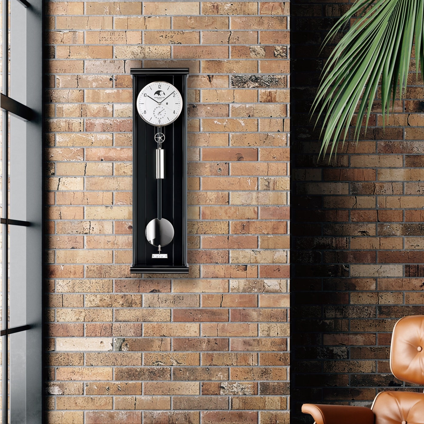 Eine Pendeluhr in schwarz von Erwin Sattler, Modell Opus PMD70 hängt an einer Backsteinwand neben einem braunen Ledersessel und einer Pflanze.