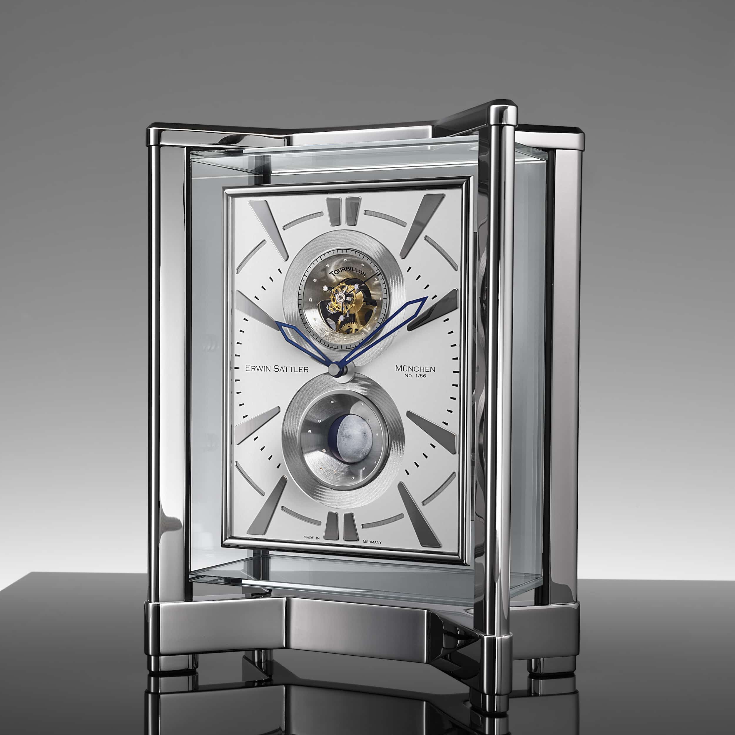Tischuhr Opus Moon Tourbillon von Erwin Sattler mit sichtbarem Uhrwerk, blauen Stunden- und Minutenzeigern und einer Kugelmondphasen Anzeige. Moderner, transparenter Gehäusedeckel und -rahmen auf glänzendem Sockel.