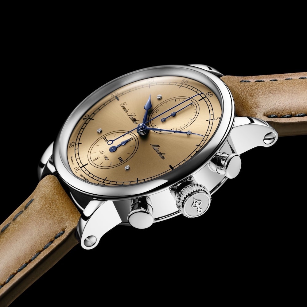 Edelstahl Armbanduhr Chronograph 66 von Erwin Sattler mit bronzefarbenem Zifferblatt, feinen blauen Zeigern und braunem Lederarmband, nah aufgenommen vor schwarzem Hintergrund.