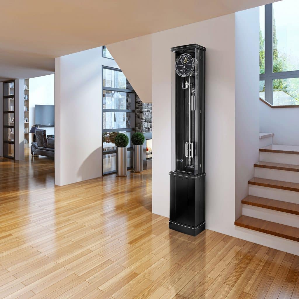 Standuhr Illumina Secunda von Erwin Sattler in einem modernen Wohnbereich mit Holzboden, neben einer offenen Treppe und einer Wand mit großen Fenstern.