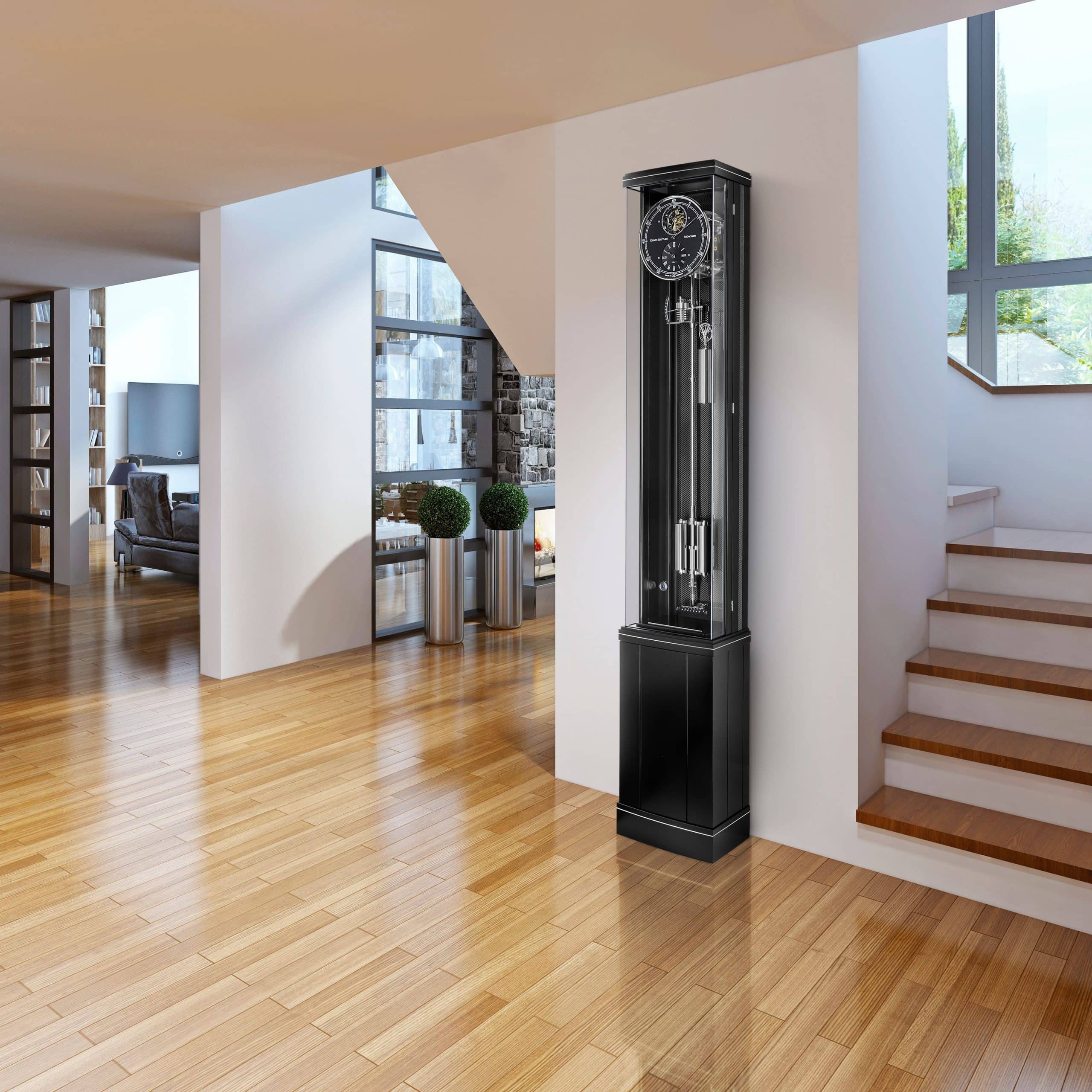 Standuhr Illumina Secunda von Erwin Sattler in einem modernen Wohnbereich mit Holzboden, neben einer offenen Treppe und einer Wand mit großen Fenstern.